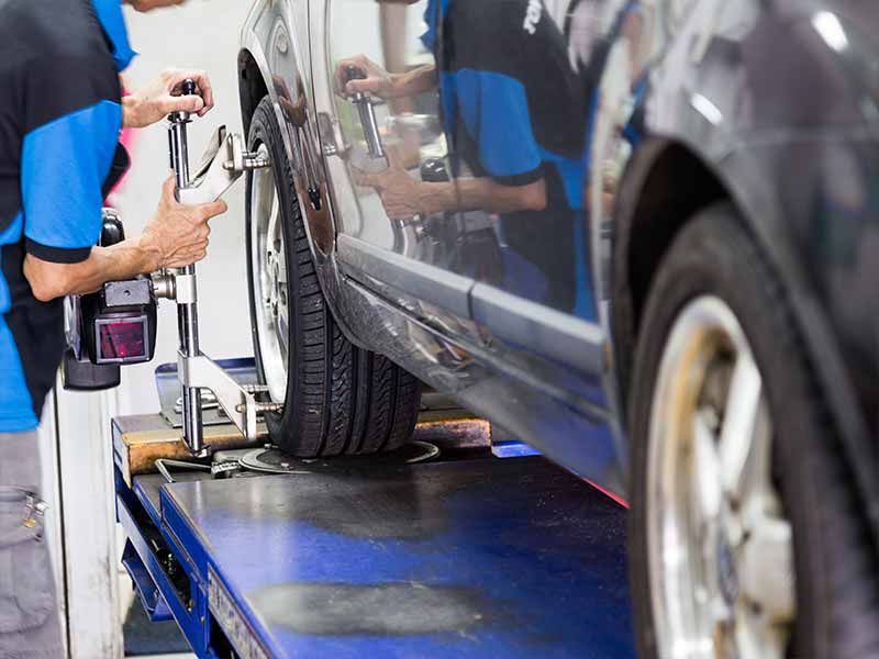 mechanic using wheel alignment equipment